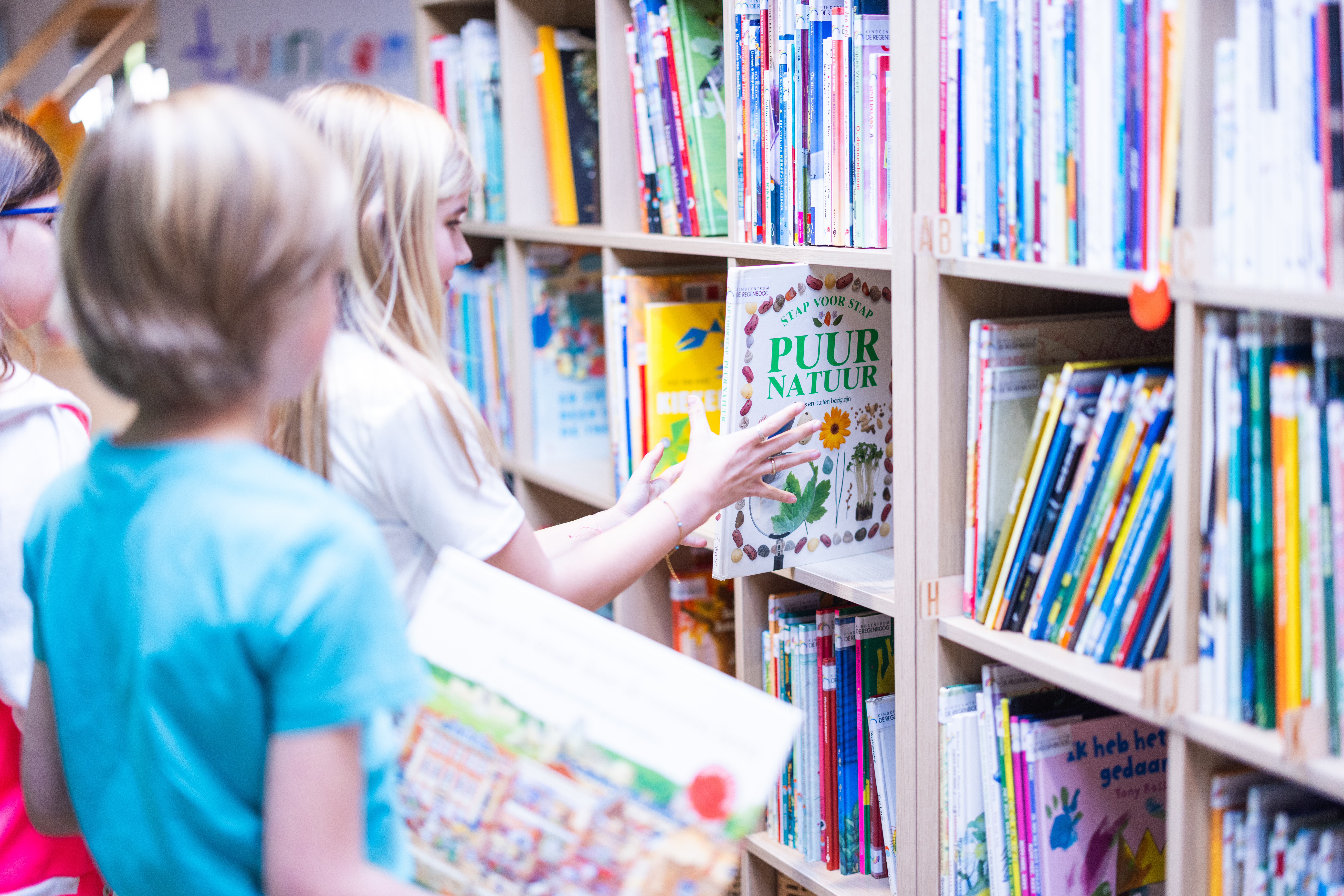 leerling van Kindcentrum De Regenboog pakt een boek uit de schoolboekenkast